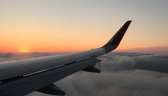 Airplane wing above the clouds at sunset